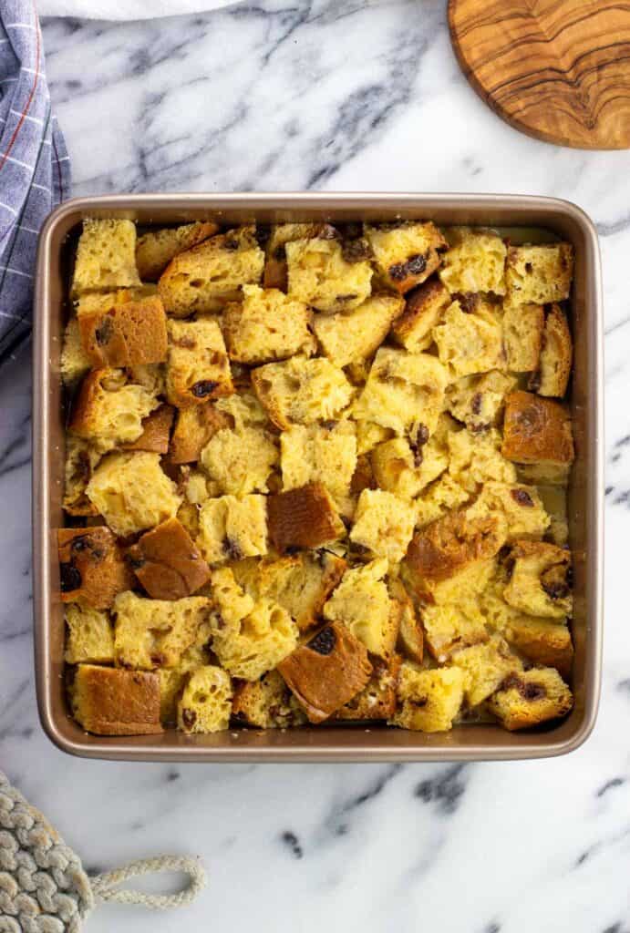 Custard poured over panettone cubes in a baking dish.