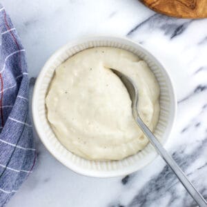 A bowl of horseradish aioli with a spoon in it.