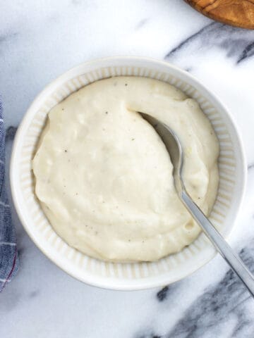 A bowl of horseradish aioli with a spoon in it.