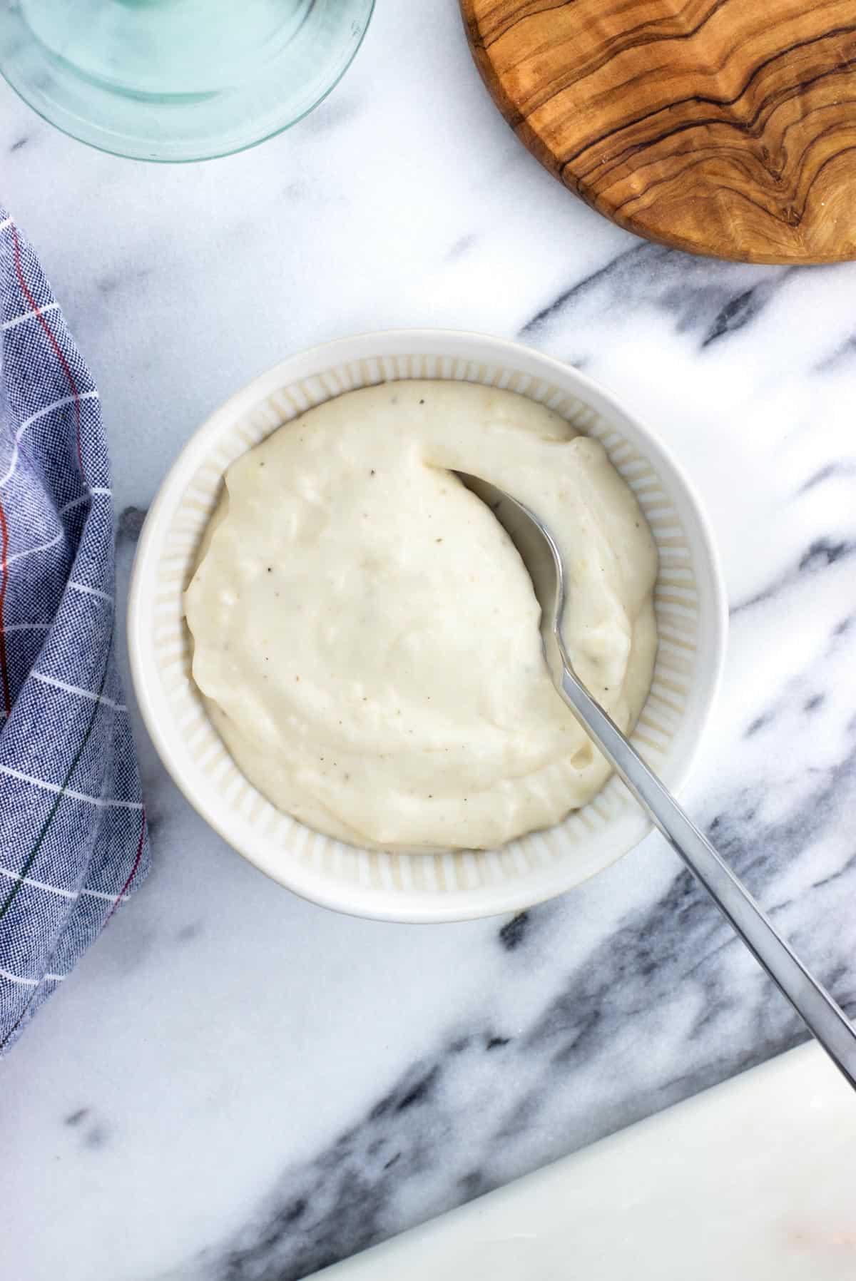 A bowl of aioli with a spoon in it.