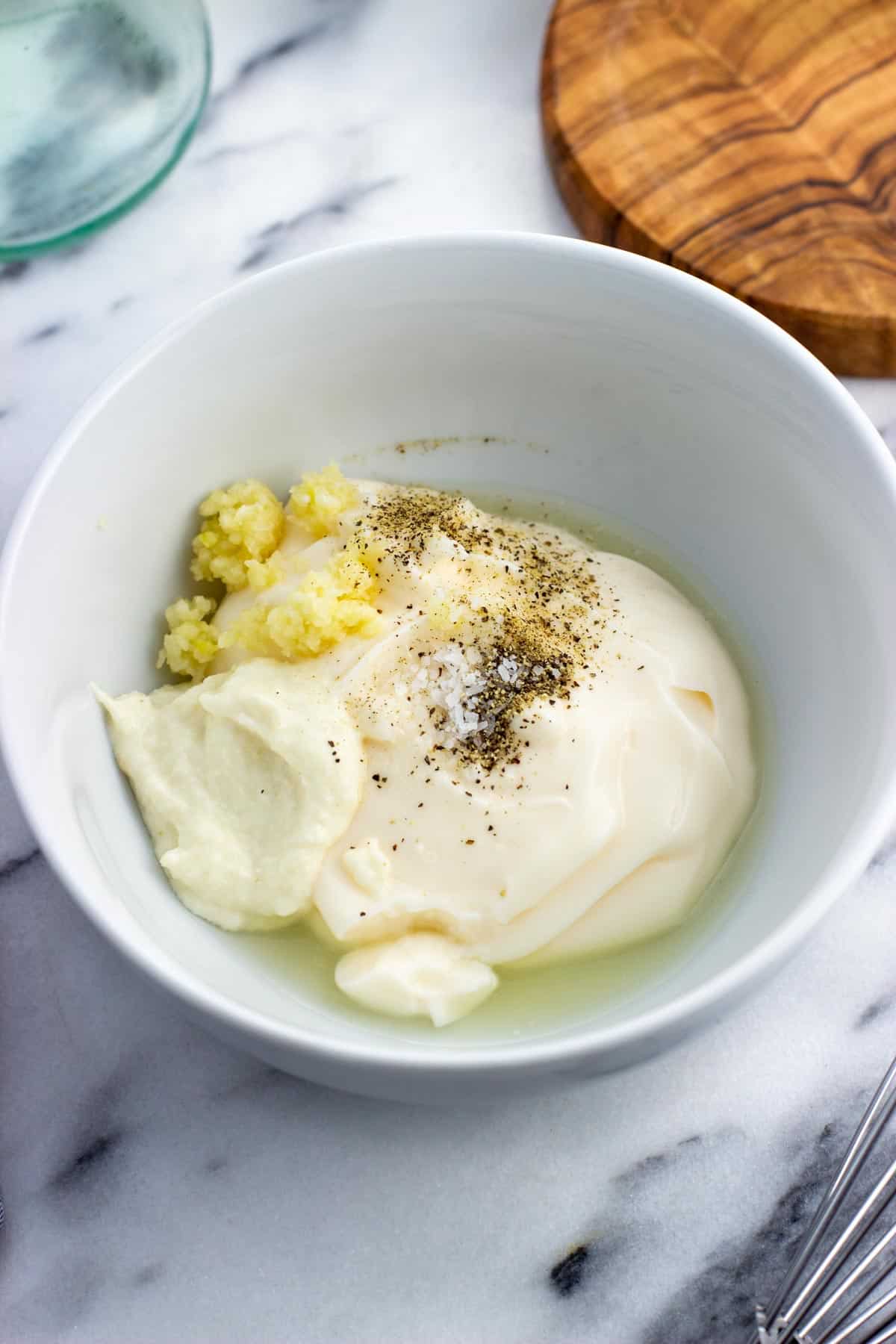 The aioli ingredients added to a ceramic bowl.