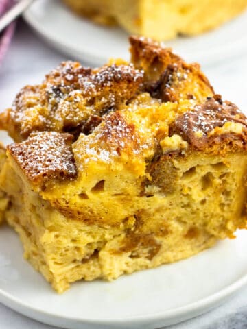 A piece of panettone bread pudding dusted with powdered sugar on a plate.