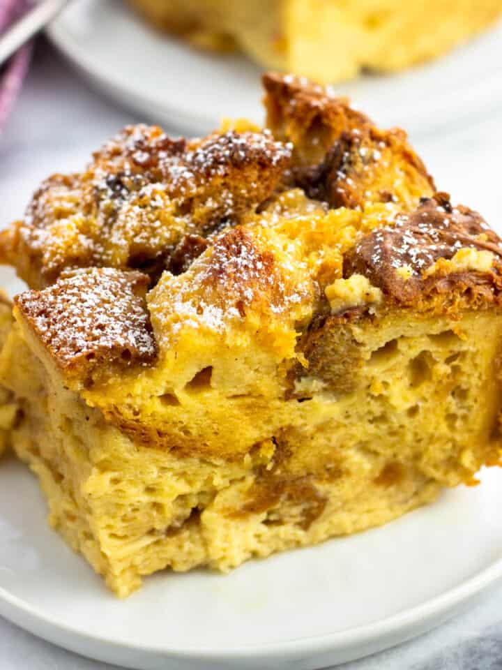 A piece of panettone bread pudding dusted with powdered sugar on a plate.