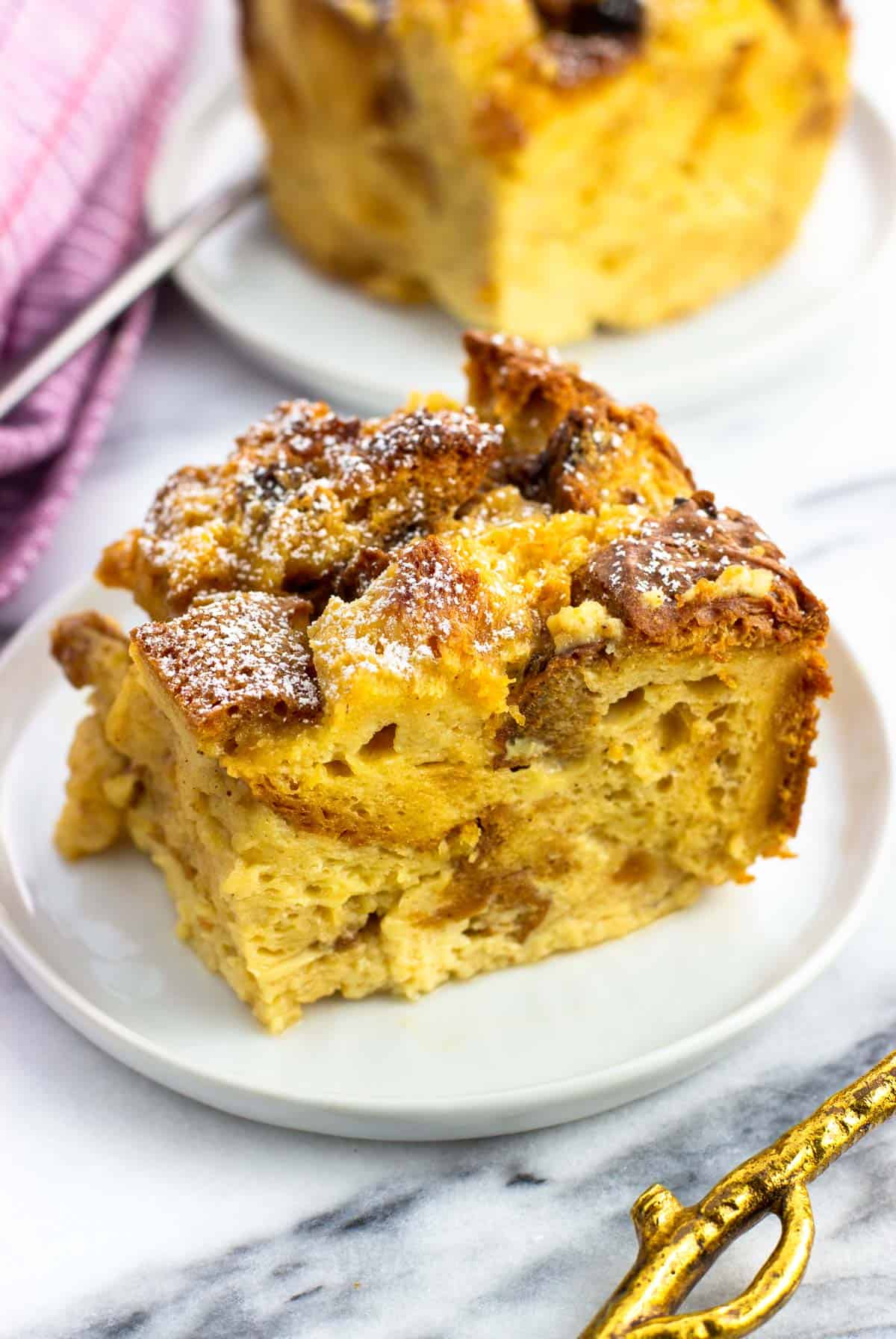 A piece of bread pudding dusted with powdered sugar on a plate.