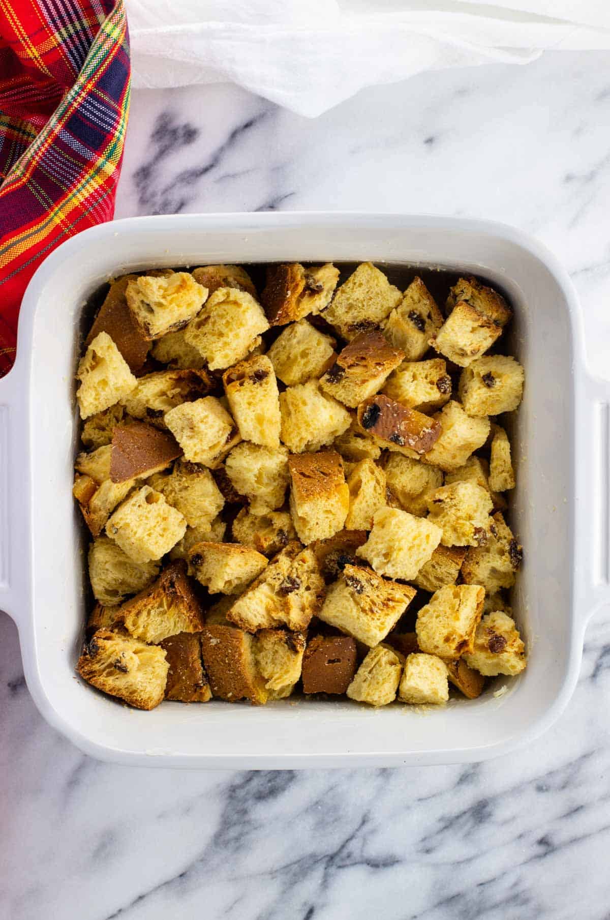 Dried panettone cubes in a square baking dish.