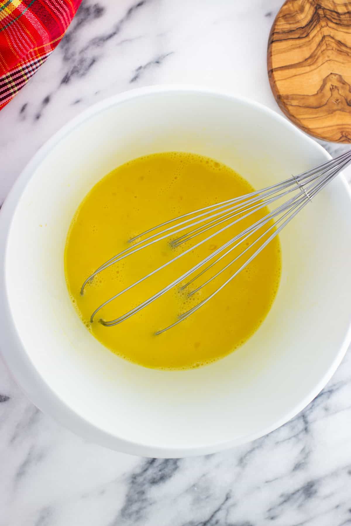 Eggs whisked together in a mixing bowl to start the custard.