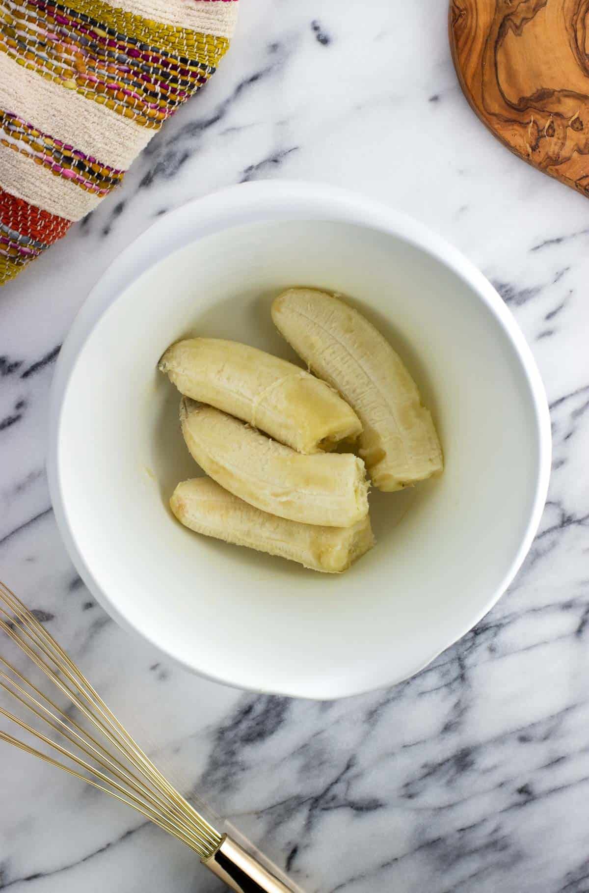 Two ripe bananas in a small mixing bowl.