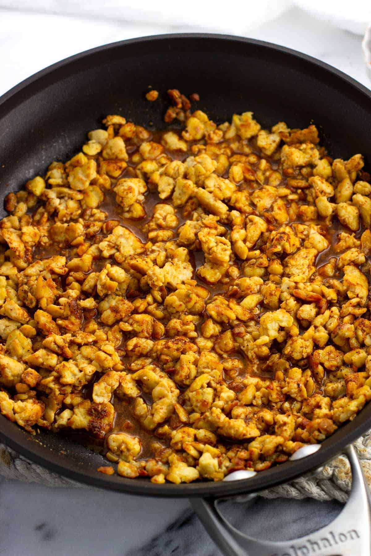 Water poured into the pan of tempeh and taco seasoning to reduce.