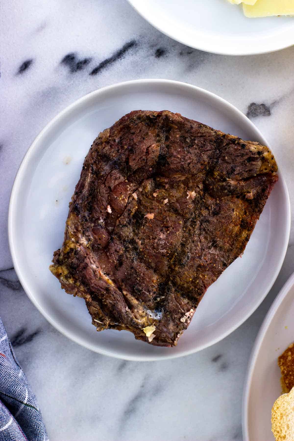A piece of cooked steak on a plate.