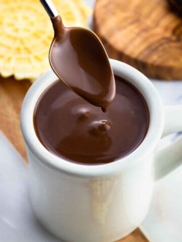 A coated spoon lifting out of the mug of thick cioccolata calda.