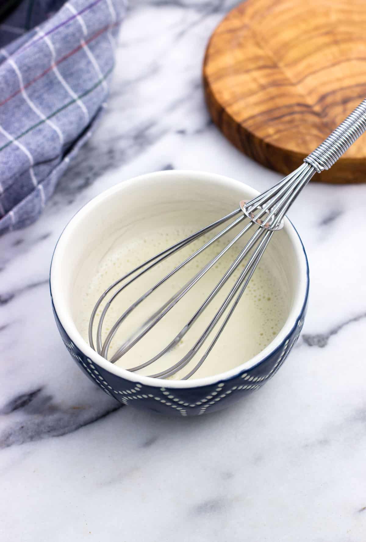 A small bowl of cornstarch slurry with a whisk.