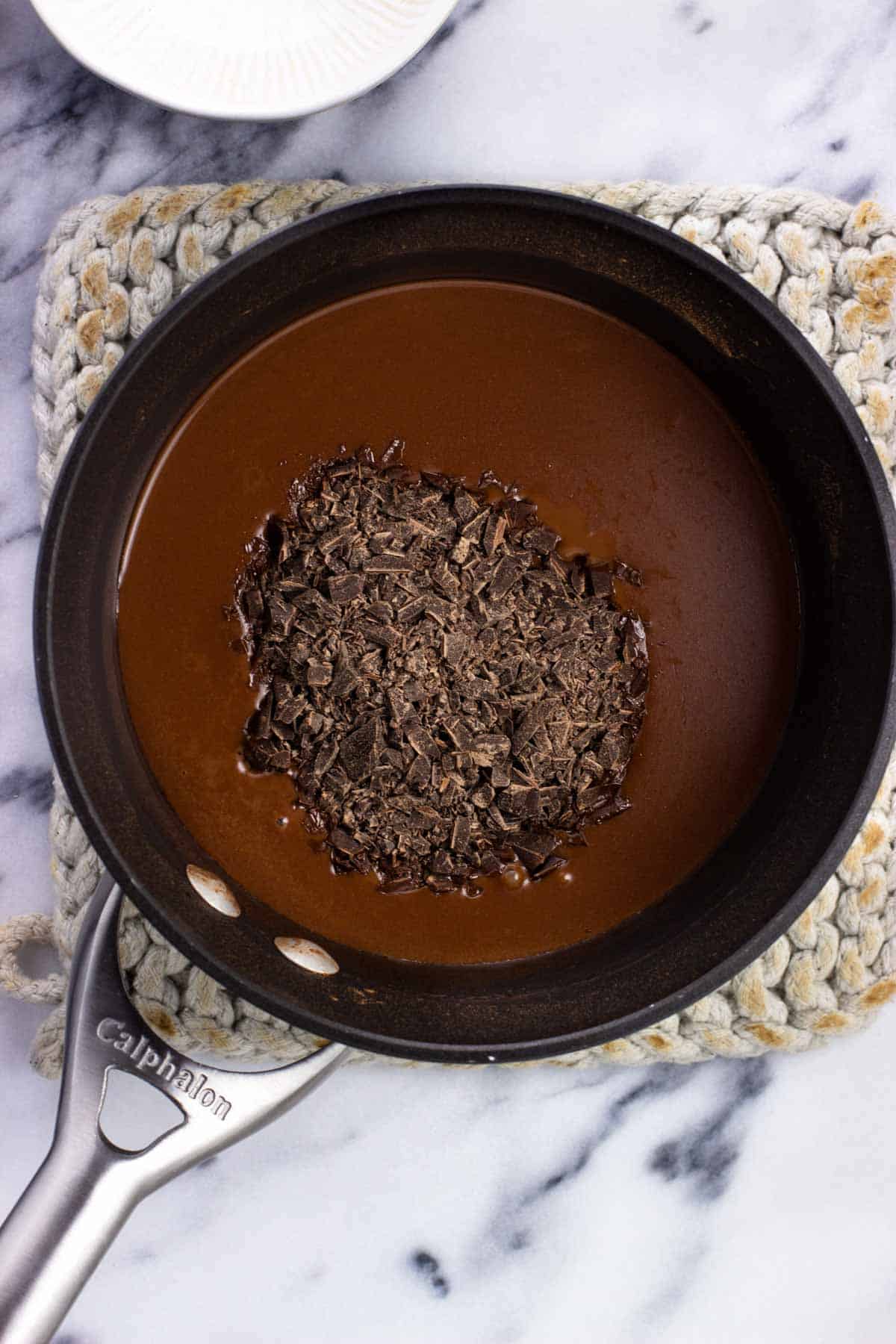 Chopped dark chocolate added to the pan of hot chocolate, before melting in.