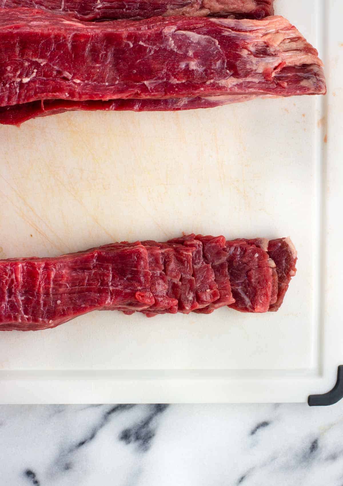 A strip of flank steak sliced into thin strips for stir fry.