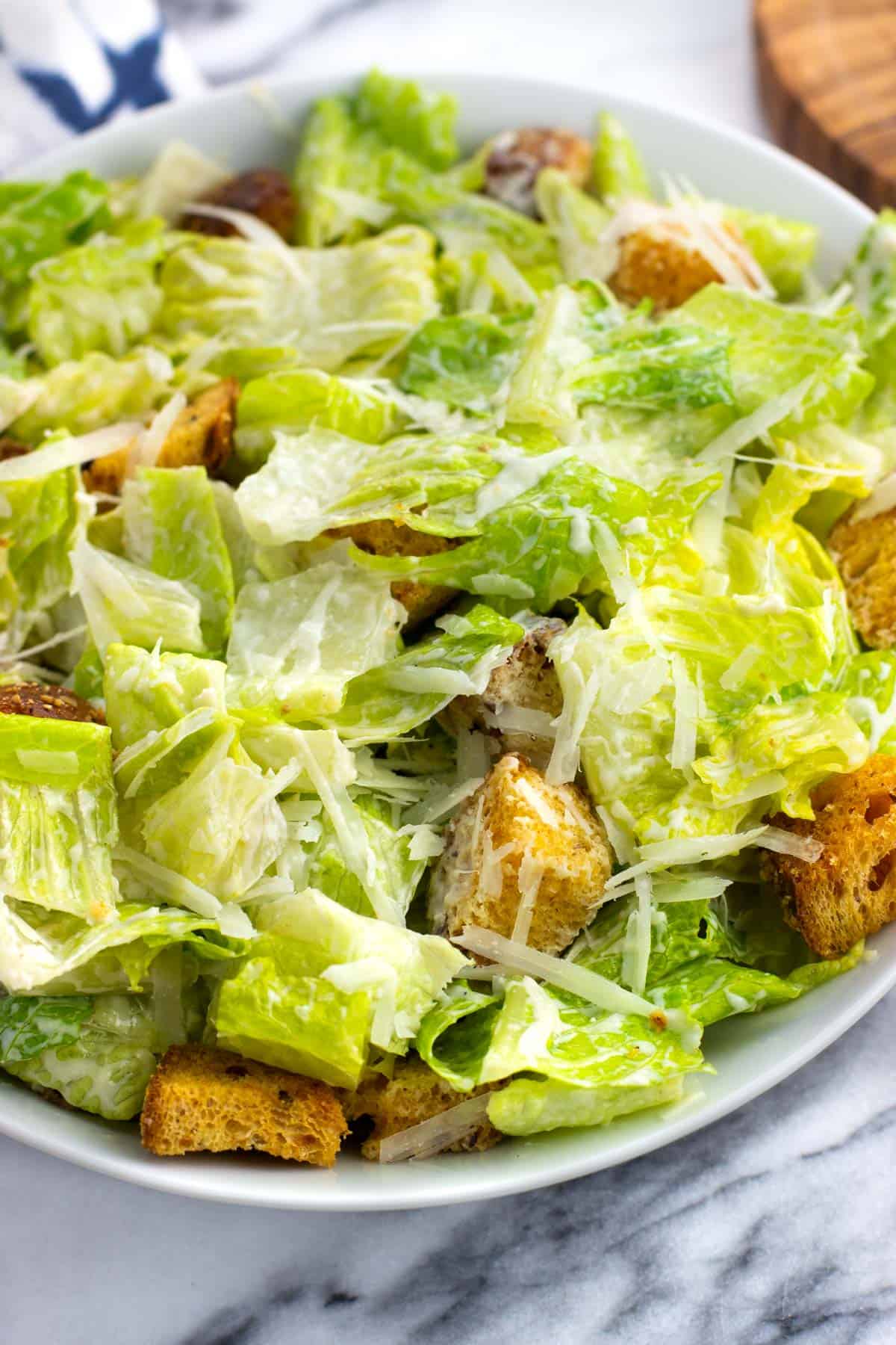 Greek yogurt caesar dressing on a salad of lettuce, croutons, and grated Parmesan.