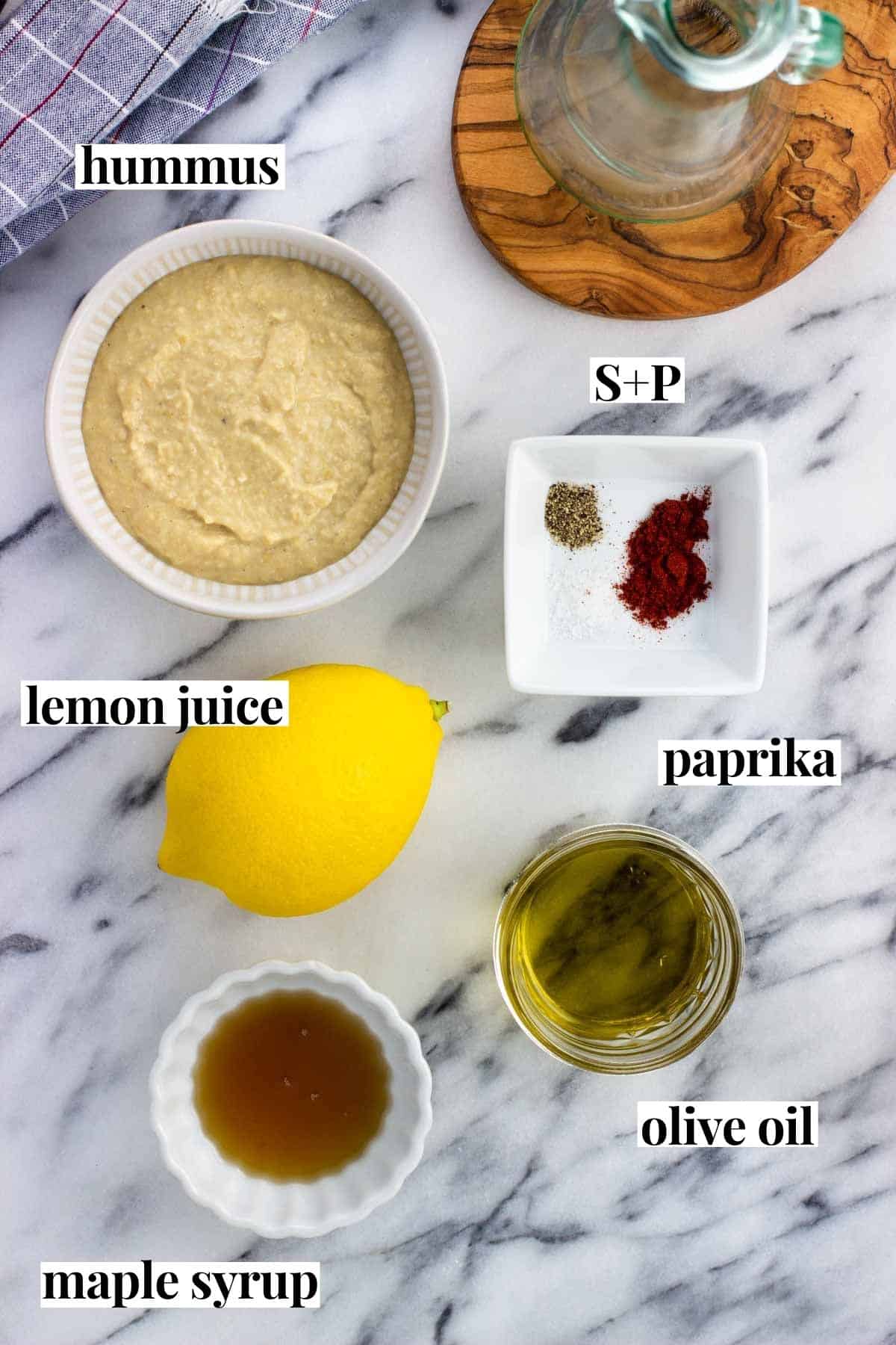 Labeled hummus dressing ingredients on a marble board.
