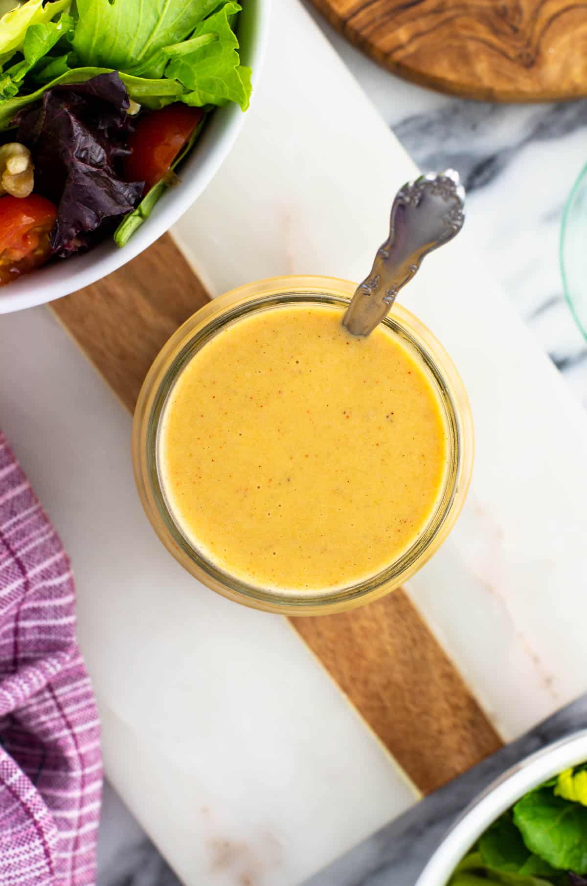 A spoon in a glass jar of dressing.