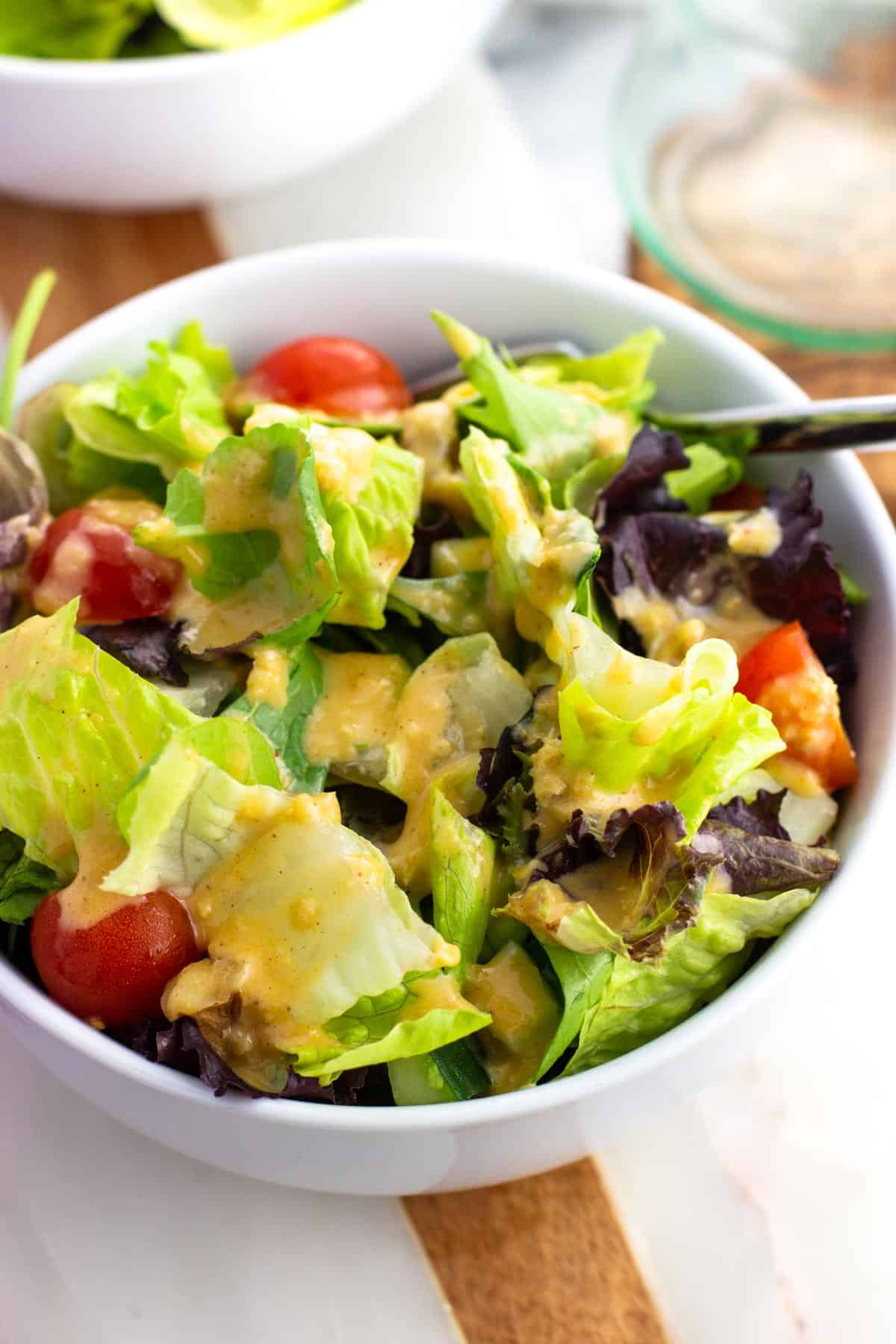 A bowl of salad dressed with hummus salad dressing.