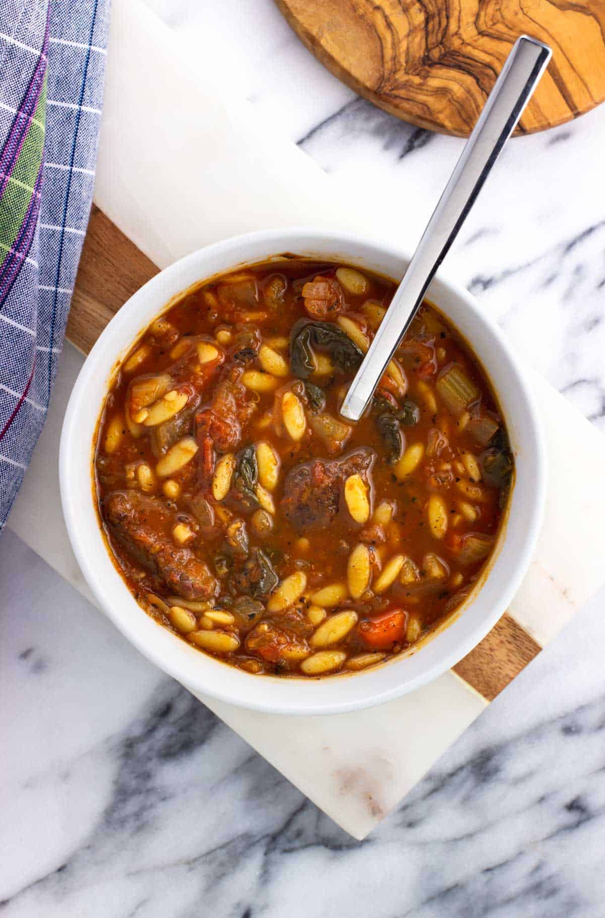 A bowl of vegetable beef soup with a spoon in it.