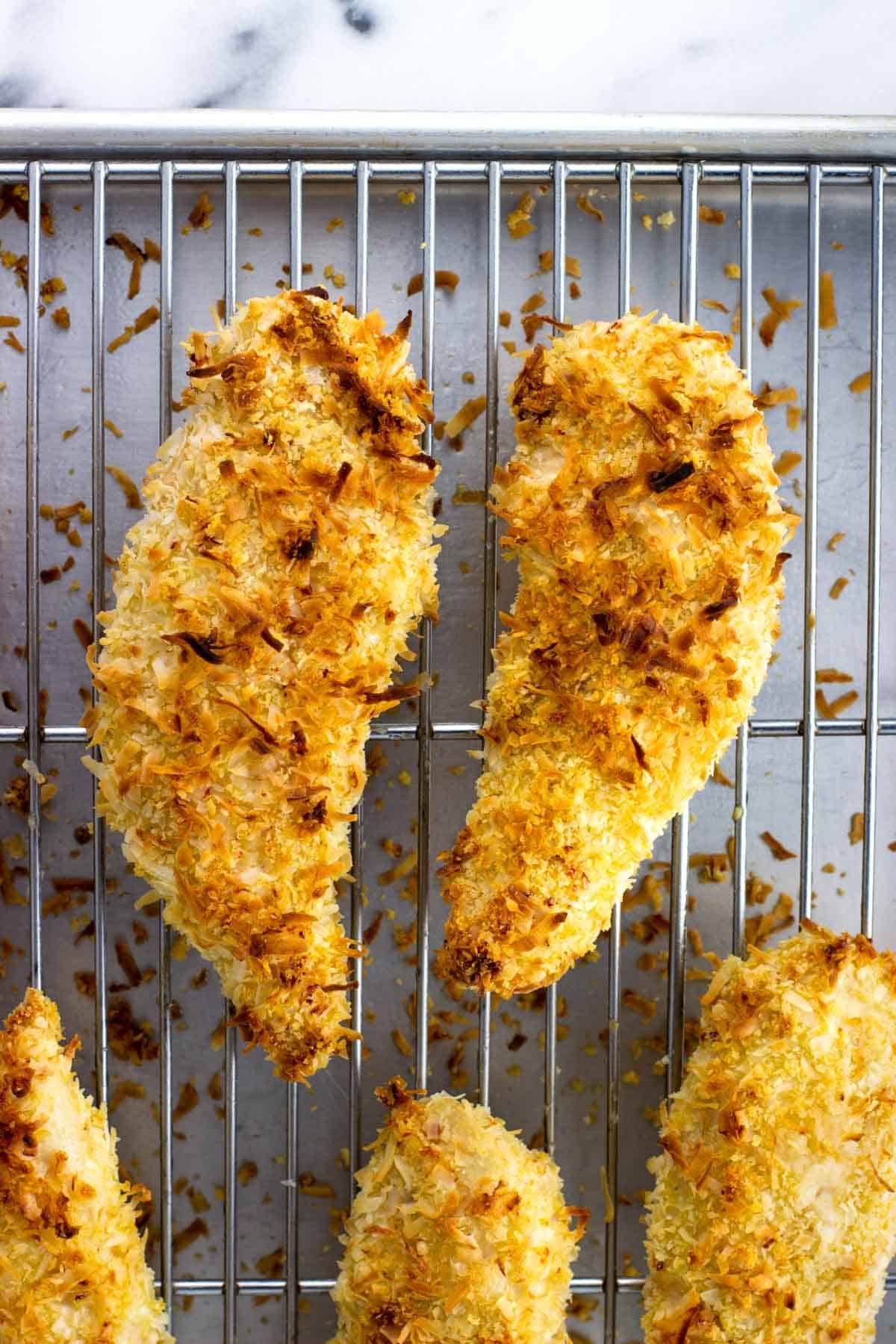 A rack of baked chicken tenders on a metal sheet pan.