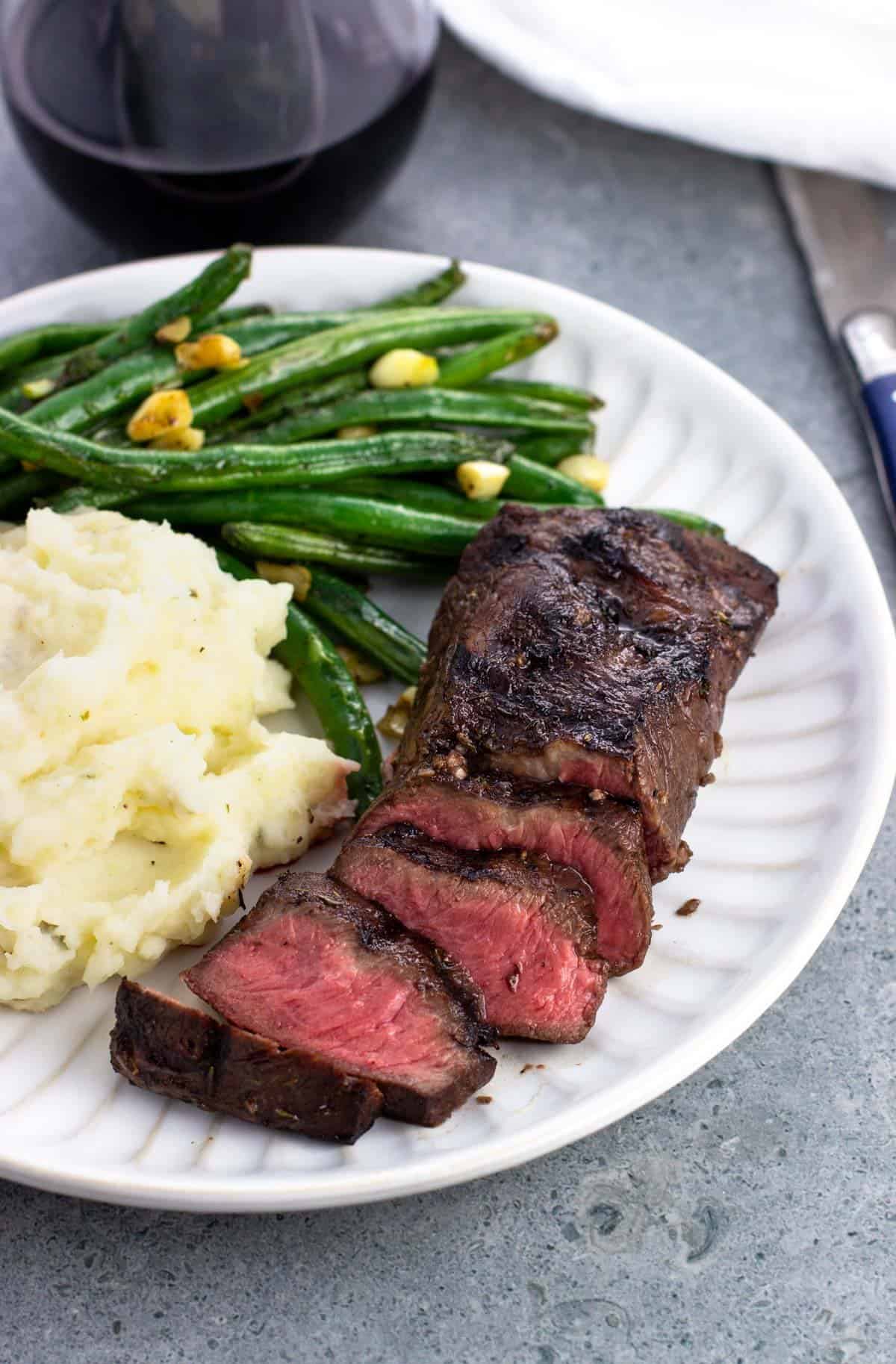 A dinner plate of steak, potatoes, and green beans.