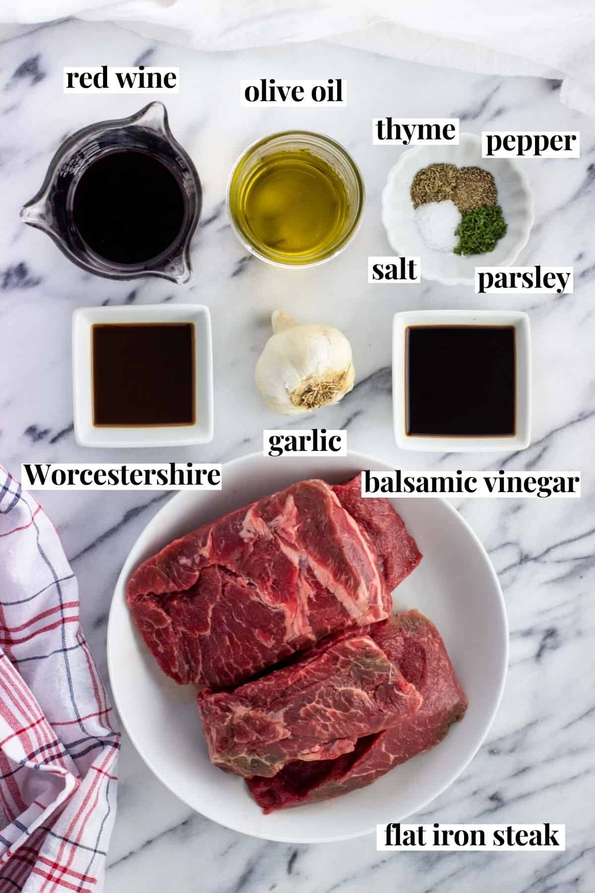 Labeled flat iron steak marinade ingredients on a marble board.