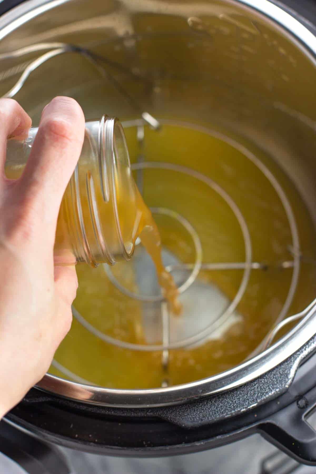 Apple cider vinegar being poured into the Instant Pot over the trivet.