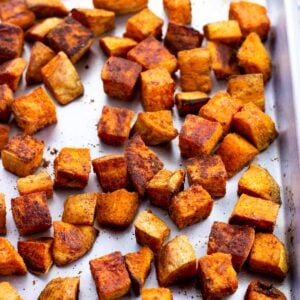 Well-roasted sweet potato cubes on a sheet pan.