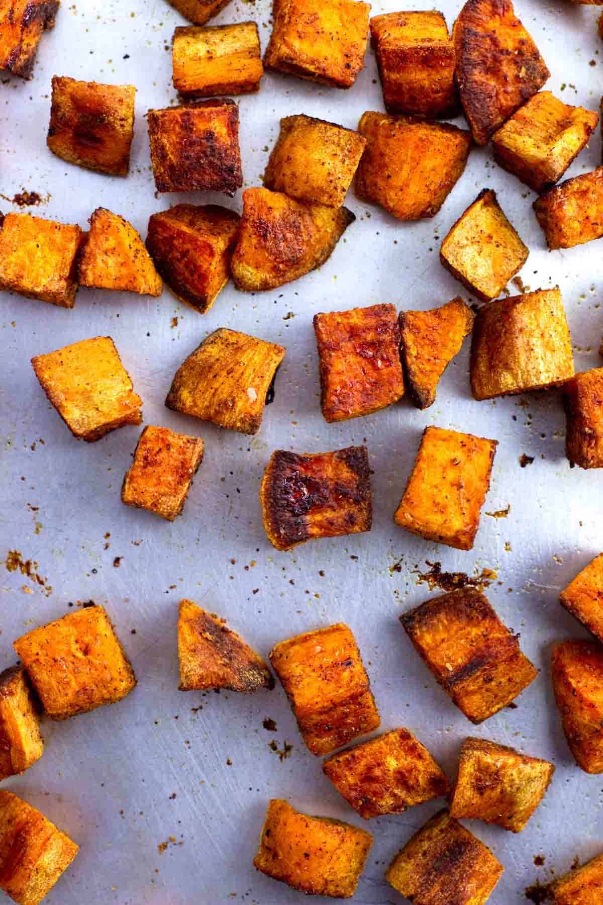 Roasted sweet potato chunks on a sheet pan.