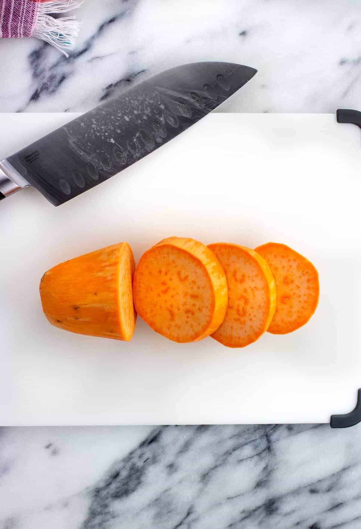 A sweet potato on a cutting board cut into sections.