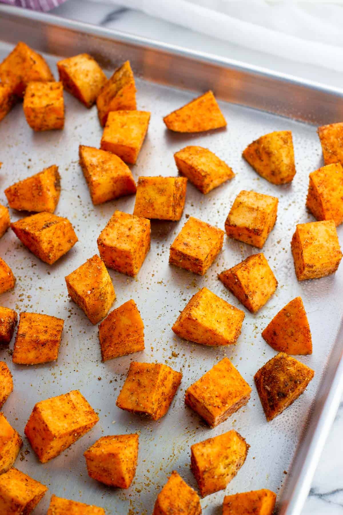 Raw sweet potato cubes on a sheet pan.