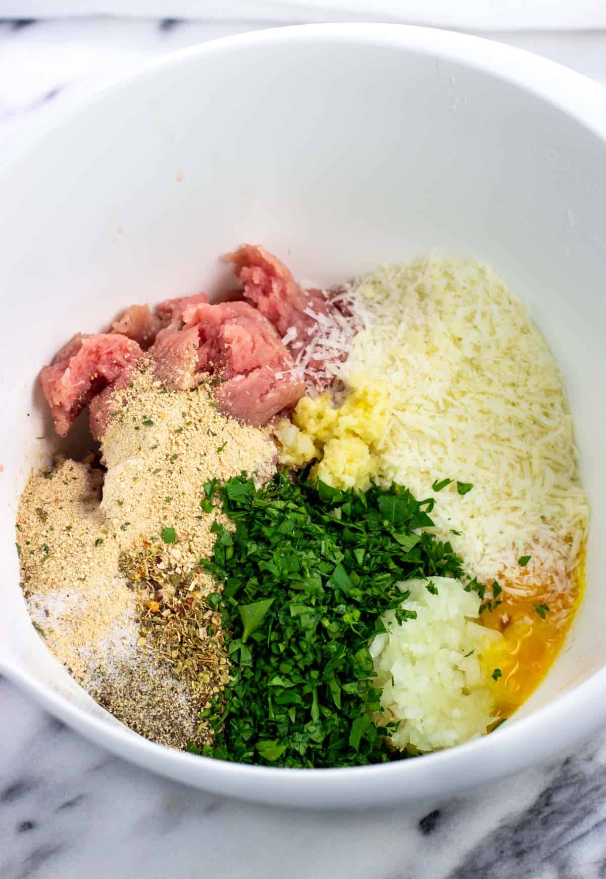 Meatball ingredients added to a large mixing bowl.