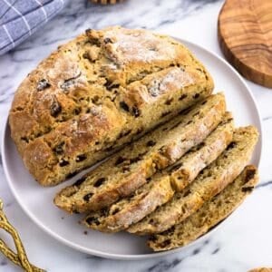 A half-sliced loaf of maple Irish soda bread on a plate.