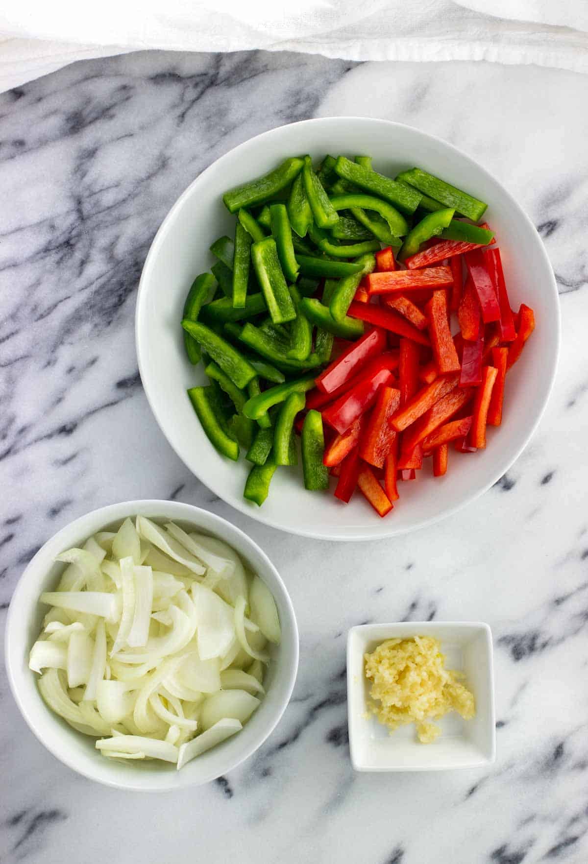 Sliced peppers and onion and garlic in containers.