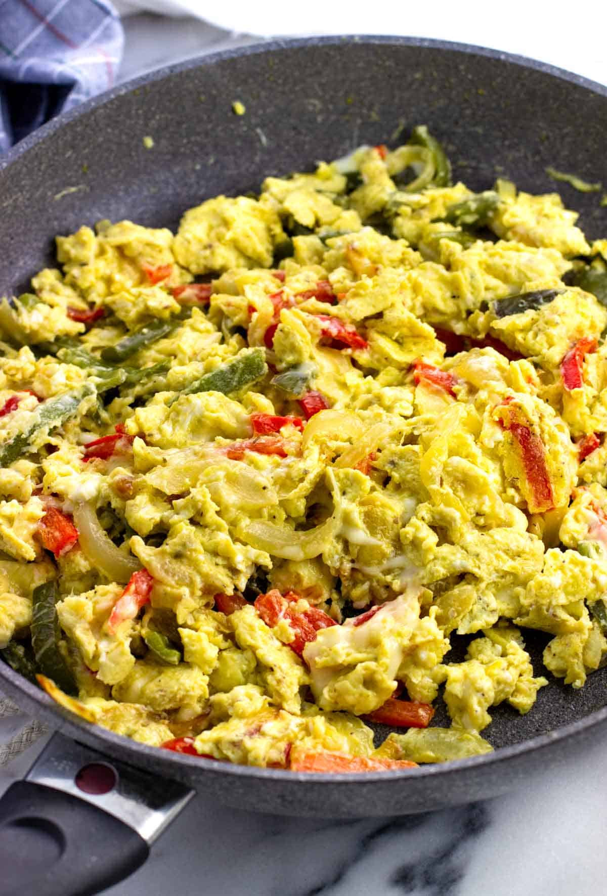 Scrambled peppers and eggs in a skillet.