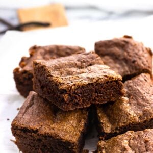 Stacked fudgy brownies on a serving board.