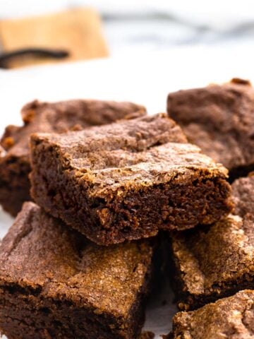 Stacked fudgy brownies on a serving board.