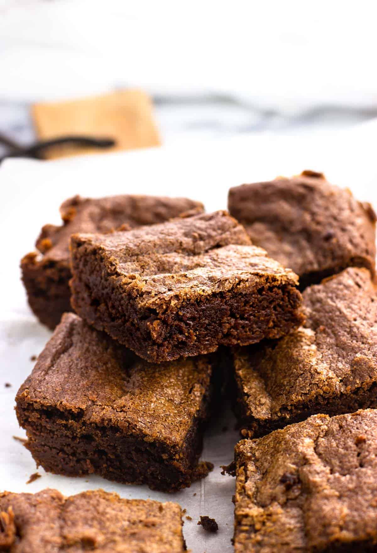 Stacked fudgy brownies on a serving board.