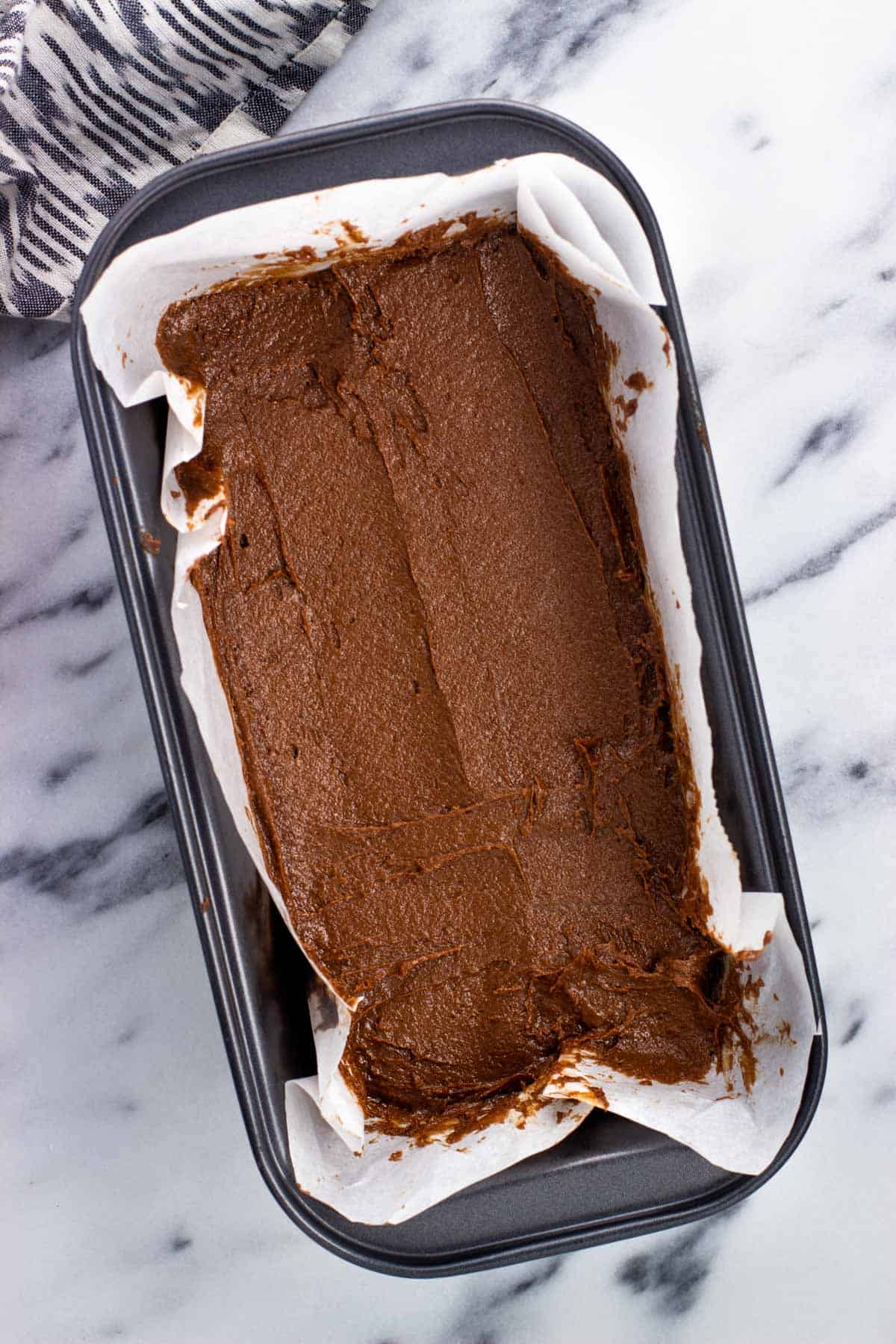 Small batch brownie batter poured into a parchment-lined loaf pan.