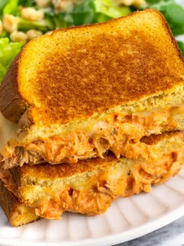 Two halves of a buffalo chicken grilled cheese stacked on top of one another.