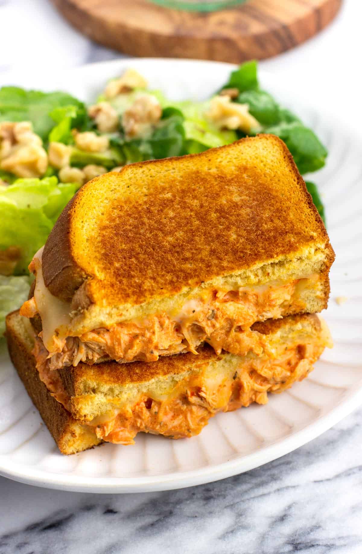 Two halves of a buffalo chicken grilled cheese stacked on top of one another.