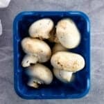 A container of whole white button mushrooms.