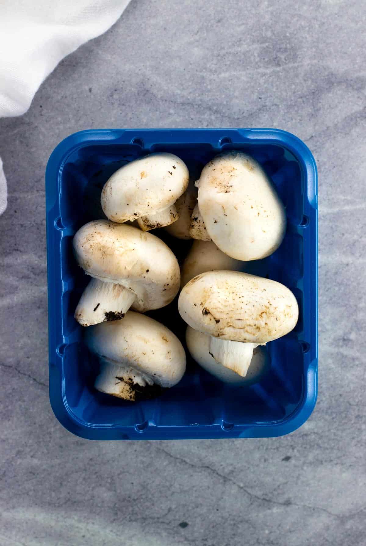 A container of whole white button mushrooms.