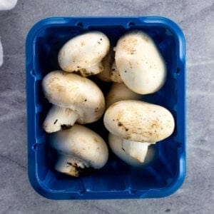 A container of whole white button mushrooms.