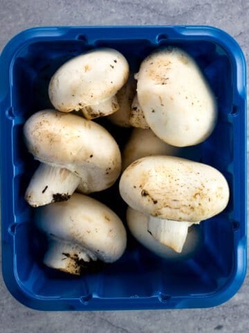 A container of whole white button mushrooms.