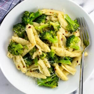 A plate of cavatelli and broccoli with a fork.