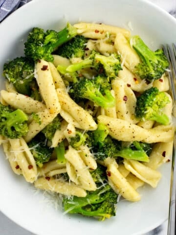 A plate of cavatelli and broccoli with a fork.