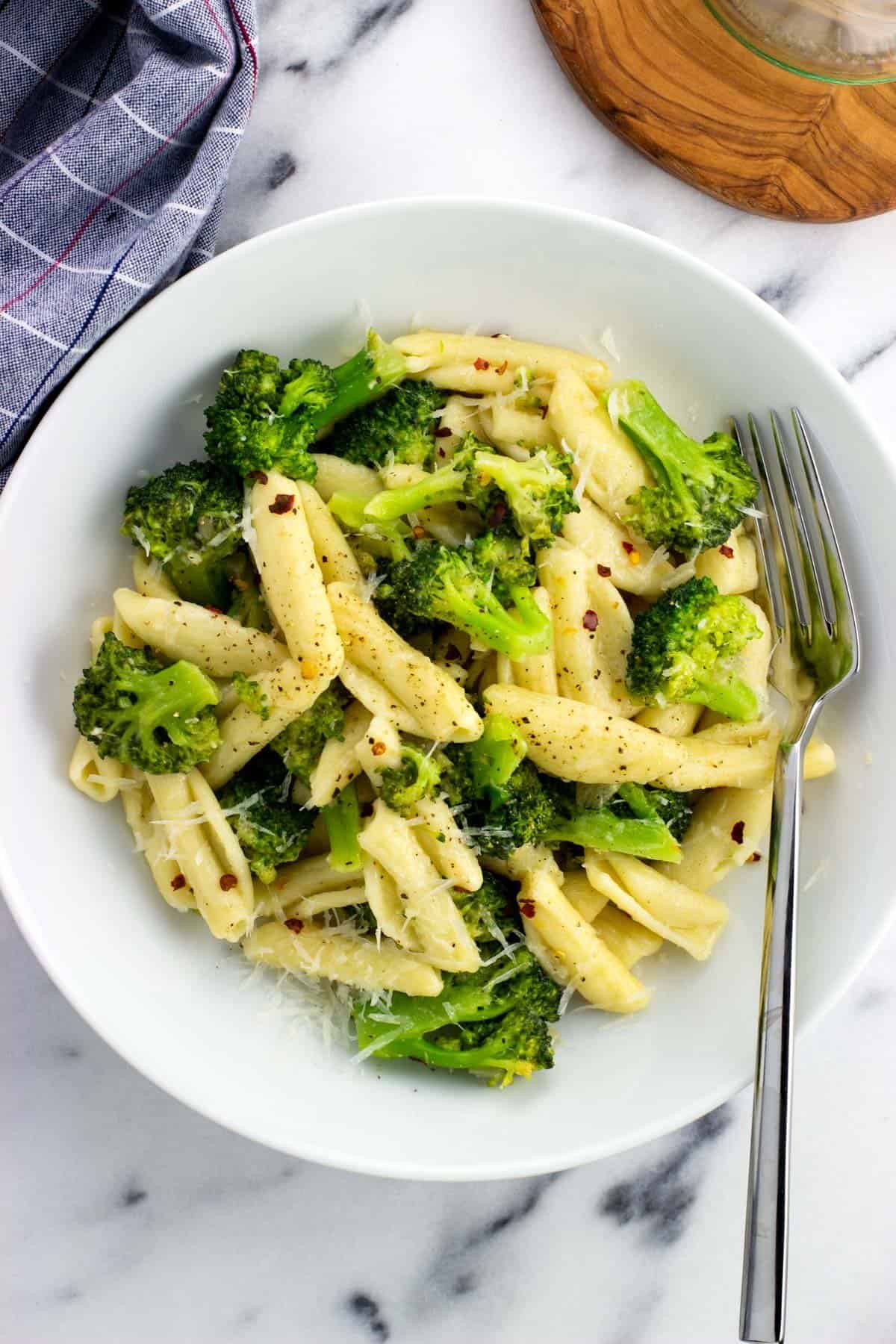 A plate of cavatelli and broccoli with a fork.