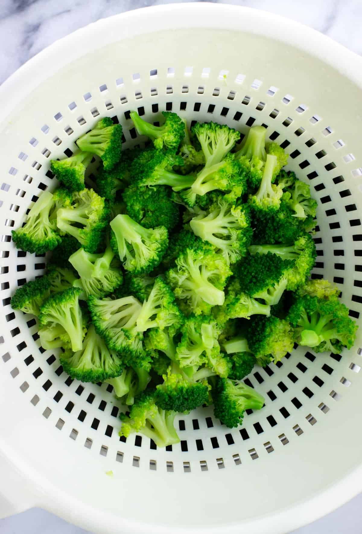 Drained blanched broccoli florets in a colander.