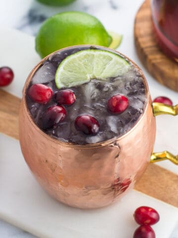 A frosty cranberry moscow mule in a copper mug.