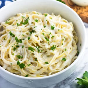 A bowl of healthy alfredo sauce coating fettuccine.